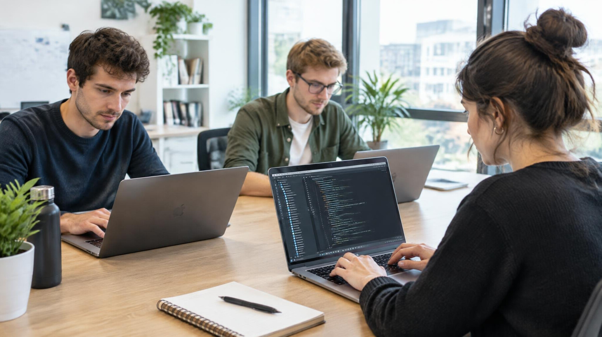 Programmers working together on laptops in a bright modern office